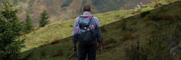 man with backpack hiking over grassy hills